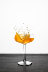 Wall Mural - A splash of an orange cocktail in a coupe glass