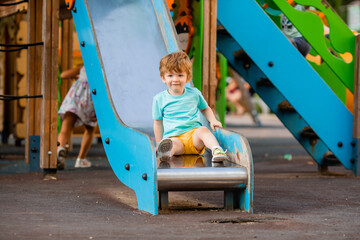 little boy of two years plays in a children's town in the summer. Children lifestyle