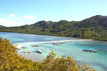 Beautiful landscape with rocks, mountain, turquoise blue water sea, white sand lonely beach, typical philippan boats and green vegetation trees in the lagoon of El Nido, palawan, Philippines Islands.