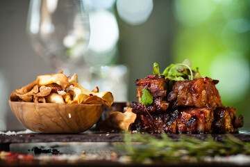 Pork ribs cooked at low temperature. Blackcurrant sauce, parsnip chips with Parmesan cheese. Delicious healthy meat food closeup served on a table for lunch in modern cuisine gourmet restaurant