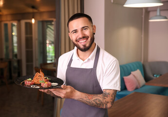 Wall Mural - Young male waiter with dish in restaurant