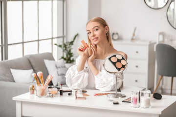 Sticker - Beautiful young woman applying foundation at home