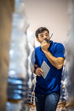 Fototapeta Na ścianę - Male dispatcher, warehouse worker checking packages while using walkie-talkie in distribution warehouse storage.