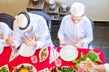 Wall Mural - Happy Arabic Muslim family praying to god prior eating and asking for god forgiveness