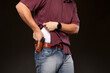Man lifting up his shirt about to draw his concealed carry pistol from his holster.