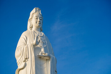 Wall Mural - Detail of Lady Buddha statue in a Buddhist temple and blue sky background in Danang, Vietnam. Closeup, copy space