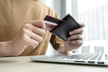 The businessman's hand is holding a credit card and using a laptop for online shopping and internet payment in the office