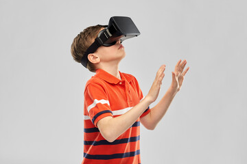 Wall Mural - childhood, fashion and people concept - boy in virtual reality headset or vr glasses over grey background