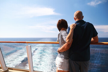 caucasian man and brunette woman in sunglasses traveling together on cruise ship,standing on balcony and enjoying with beautiful view of Caribbean sea