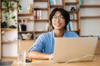 © Drobot Dean - Image of asian joyful man working with laptop while sitting at table