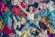 High angle above view photo of crazy funny lady spring cleaning household lying many clothes heap stack floor raise arms legs shopper surrounded sales stuff do not care enjoy mess indoors