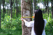 © Ann Patchanan - Female botanists in white coat at the forest.Young asian scientist woman looking at the bark of the rubber tree and measure the trunk size by using a tape measure researches rubber latex development