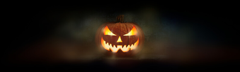 Wall Mural - one spooky evil halloween lantern, jack o lantern, with glowing eyes and face on a dark background.
