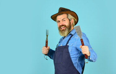 happy hipster hold cooking utensils for barbecue. bearded man chef. Tools for roasting meat outdoors. Picnic and barbecue. ready for barbecue party. Culinary concept. summer weekend. copy space