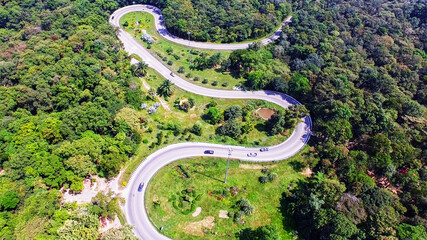 aerial view from drone of cars are going through a curve road on the mountain with green forest. the