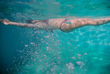 Fototapeta Łazienka - young woman diving floating in a pool. summer and fun lifestyle. selective focus on bubbles.
