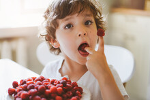 Cute Beautiful Little Boy Eating Fresh Raspberries. Healthy Food, Childhood And Development. Happy Kid At Home.