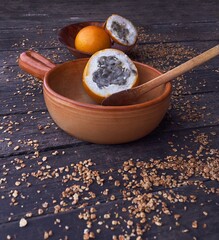 Vertical shot of two granadilla fruits in two different wooden bowls on a dark surface