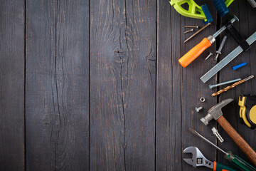 Work tool of the wizard. Tape measure, screwdriver, hammer, wrenches, clamp, screws, drills and other tools on a wooden surface.