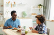 © AnnaStills - Father and son sitting at the table smiling to each other and having breakfast in the kitchen at home