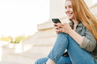© Drobot Dean - Portrait of young woman sitting on stairs with mobile phone