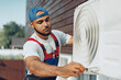 © fotofabrika - Young black man repairman checking an outside air conditioner unit