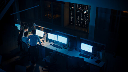 Poster - Late at Night In Modern Office: Diverse Team of Successful Businessmen and Businesswomen Gather Around Computer, Have Discussion, Find Problem Solution, Finishing Project Together. High Angle