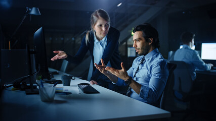 Aufkleber - Confident Businessman Uses Desktop Computer, His Female Project Manager Explains Specific Tasks, Account Handling, Strategy. Professional People Debating and Arguing Late at Night in Corporate Office