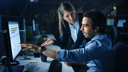Poster - Confident Businessman Uses Desktop Computer, His Female Manager Explains Specific Tasks, Account Handling and Strategy. Professional People Discussion and Arguing Late at Night in Corporate Office.