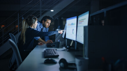 Poster - Confident Businessman Uses Desktop Computer, Her Male Manager Explains Specific Tasks, Account Handling and Strategy. Professional People Debating, Discussing Issues Late at Night in Corporate Office