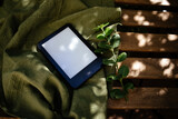 Fototapeta Lawenda - Ebook Reader on a wooden table with a green plant