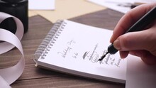 Unrecognizable person with ink pen writing to do list in notepad on table while preparing for wedding day
