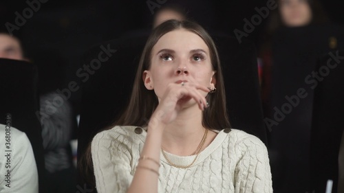 Cuadros en Lienzo Close up of a scared young woman using her hands to cover her face while watching a scary movie