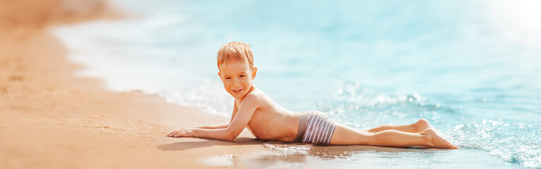 Fototapete - Boy lying on the beach at sea in summer