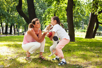 young pretty caucasian mother walking with little cute daughter and dog fox terrier, lifestyle people concept