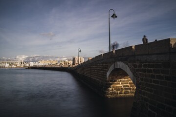 Poster - Closeup shot of a brisk-stone bridge with a city on the background after sunset