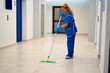 A cleaning lady mops the floor in an office building