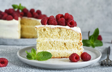 Wall Mural - Slice of cake. Birthday cake with cream cheese and raspberries and mint on a concrete kitchen background.