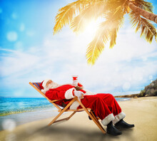 Santa Claus Relaxing On A Deckchair In A Tropical Beach