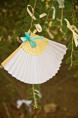 Sticker - Shallow focus shot of a white handheld folding fan with a blue bow hung from a tree