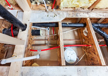 Bathroom Remodel Showing Under Floor Plumbing Work Connecting Old Copper Pipes To New Plastic Ones And Moving Vent Pipes