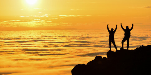 Wall Mural - Silhouette of a man standing on a rock at sunset