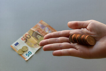 Euro coins in hand.Banknote and more coins on  back ,isolated grey background.Saving money and financial crisis concept.