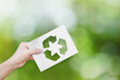 © banphote - Environment concept. Hand holding white paper with recycle symbol on green bokeh background.