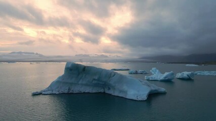 Wall Mural - A high quality 4K footage of the Glacier Lagoon Jokulsarlon in Iceland during the golden hour at colorful sunset lights. Lagoon full of icebergs is one of the most scenic places to visit in Iceland