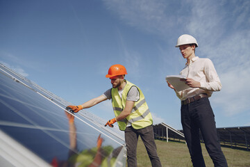 Wall Mural - Businessman and worker near solar energy batteries. Business client showing photovoltaic detail to foreman. Two men making deal.