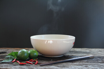 Wall Mural - Bowl of hot soup with steaming on wooden table on black background selective focus. hot food concept.