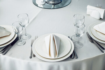 Restaurant tables set for celebration with plates, cutlery, napkin and glasses