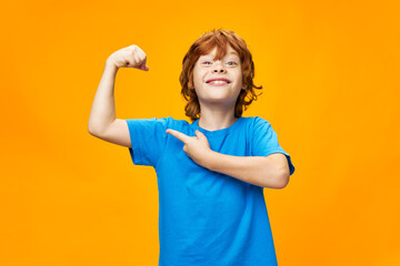 Wall Mural -  strong red-haired boy points to the muscles of his arms