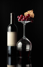 Bottle Of Red Wine And An Inverted Glass With Wine On A Black Background.